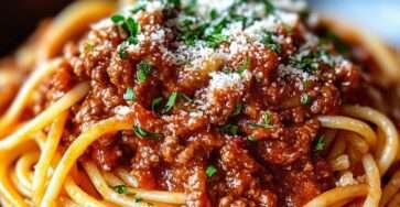 Assiette de spaghetti bolognaise garnie de sauce ragù, parmesan râpé et persil frais.