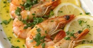 Crevettes à l’ail et au beurre citronné sautées, garnies de persil frais.