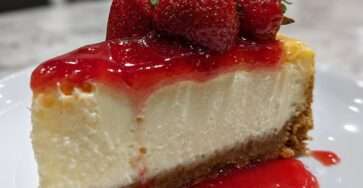 Cheesecake crémeux sur base biscuitée, nappé de coulis de fraises et décoré de fraises fraîches.