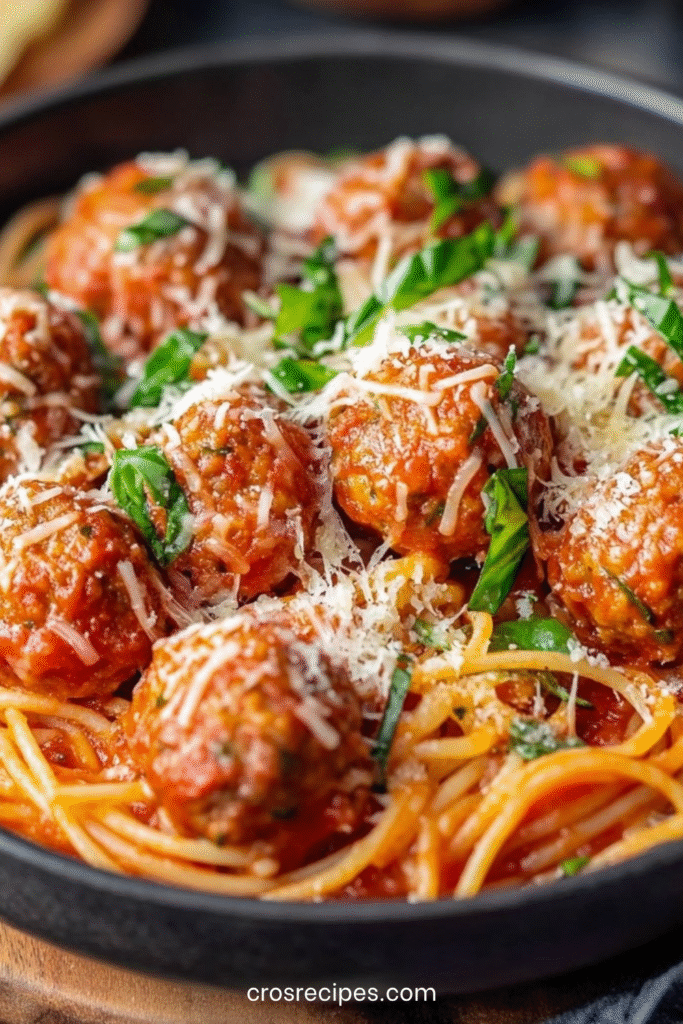 Plat de spaghettis gratinés avec boulettes de viande italiennes, mozzarella fondue et sauce tomate maison.