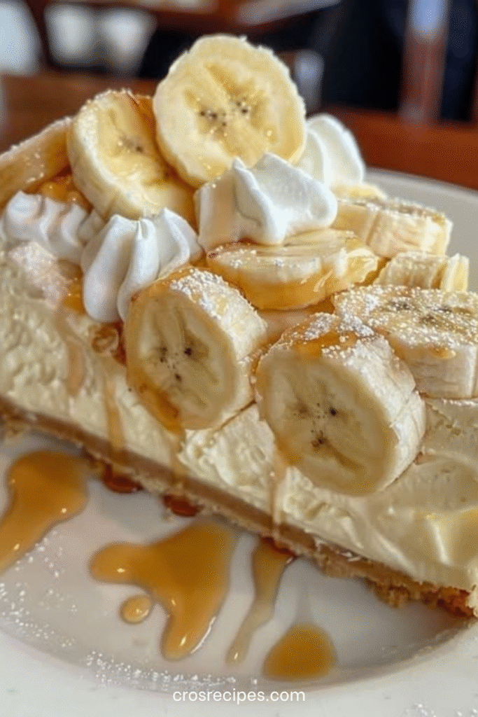 Cheesecake à la crème de banane, garni de crème fouettée, de tranches de banane et d’un filet de caramel.