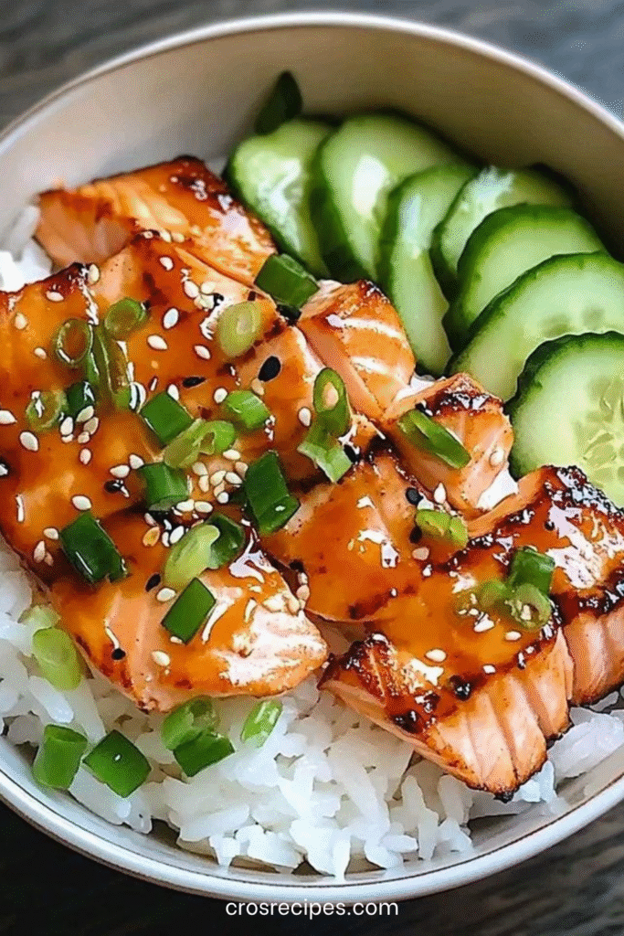 Bol de saumon teriyaki laqué servi sur du riz avec concombre frais, graines de sésame et ciboulette.