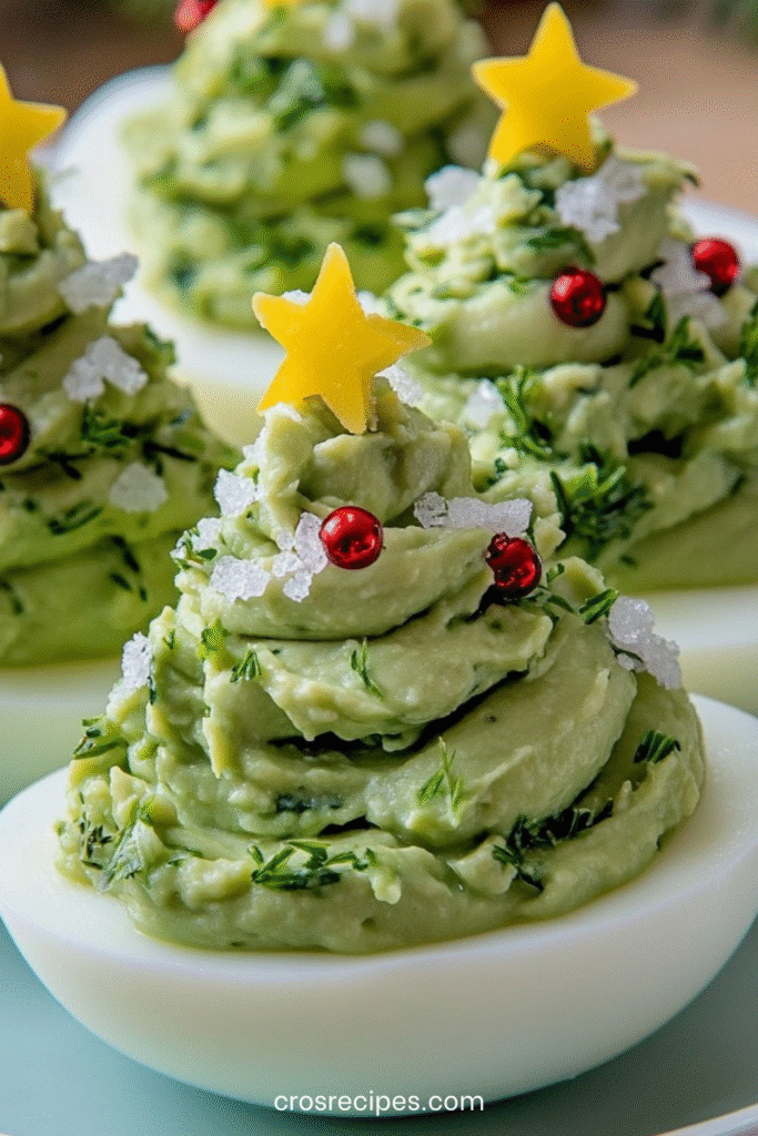 Œufs farcis garnis de guacamole en forme de sapins de Noël, décorés de perles rouges et d’étoiles de fromage.
