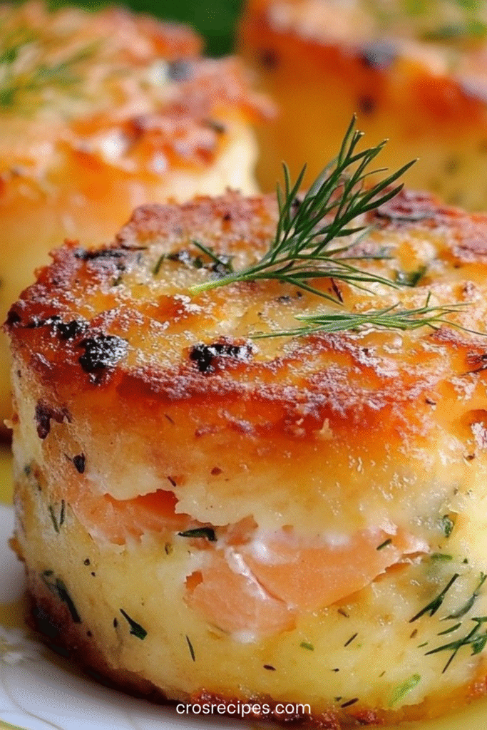 Mini cakes salés au saumon et à l’aneth, dorés et moelleux, présentés sur une assiette posée sur une table en bois clair.