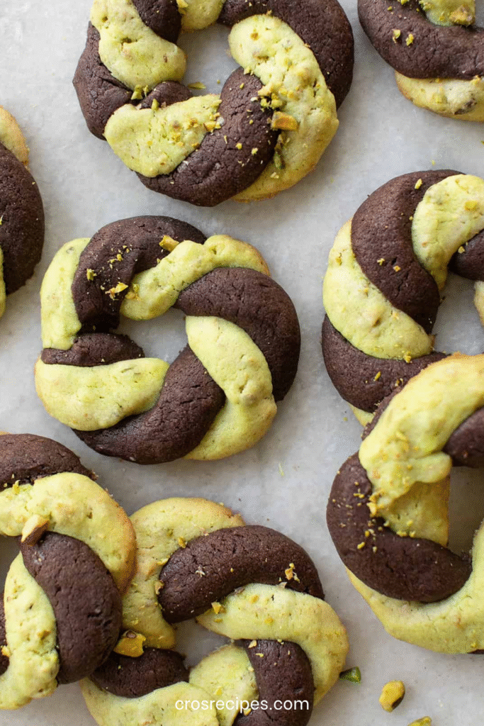 Cookies tressés bicolores chocolat pistache en forme de couronnes dorées et torsadées.
