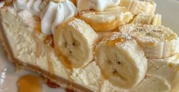 Cheesecake à la crème de banane, garni de crème fouettée, de tranches de banane et d’un filet de caramel.