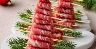 Brochettes en forme de sapins composées de tranches de saucisson pliées, décorées de romarin et d’une étoile comestible.
