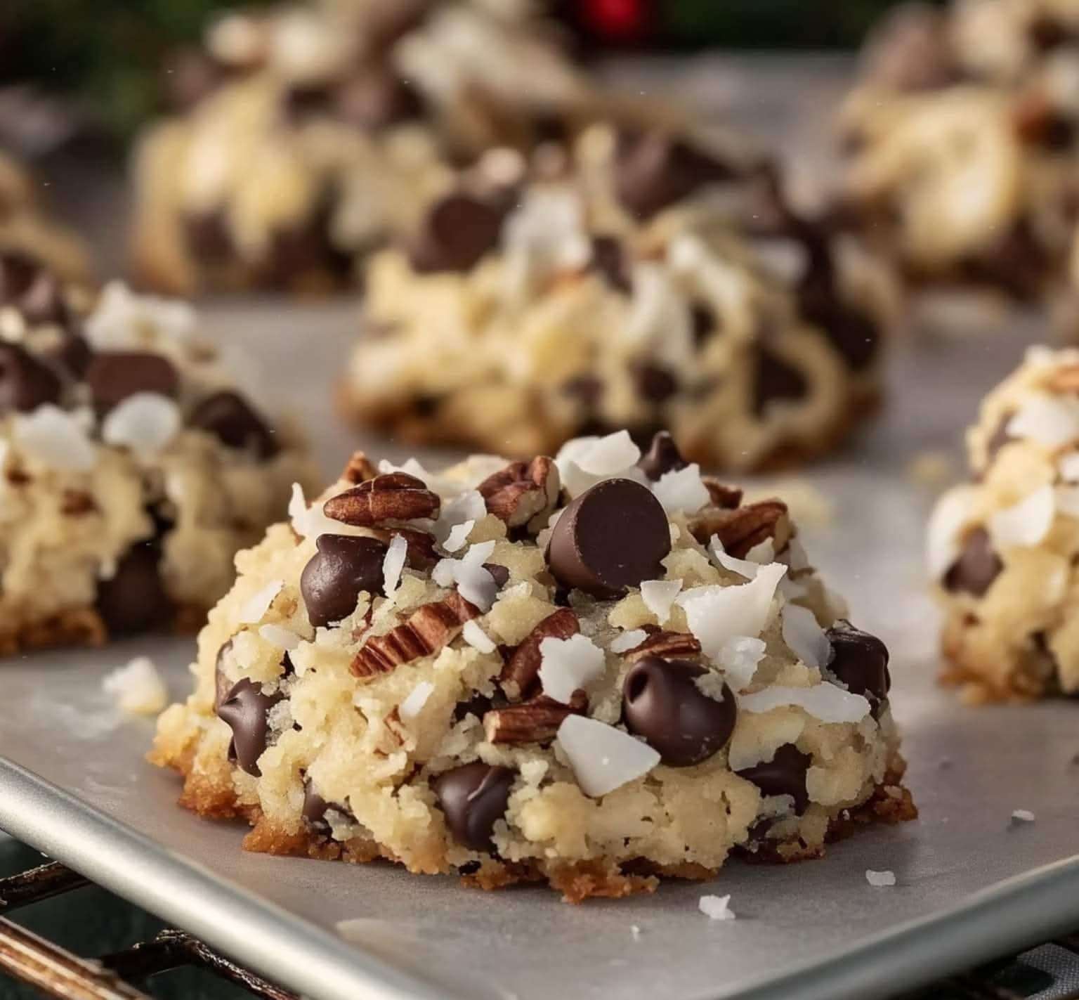 Biscuits de Noël moelleux à la noix de coco, chocolat et noix de pécan dorés sur une plaque.