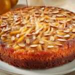 Gâteau renversé aux poires caramélisées et amandes effilées, doré, servi sur un plat.