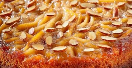 Gâteau renversé aux poires caramélisées et amandes effilées, doré, servi sur un plat.