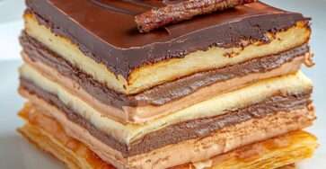 Mille-feuille au chocolat et crème pralinée composé de couches de pâte feuilletée dorée, crème pralinée et ganache au chocolat, décoré de copeaux de chocolat.