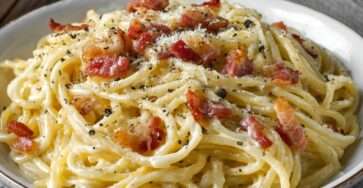 Assiette de spaghetti carbonara français avec lardons croustillants et sauce crémeuse au fromage.