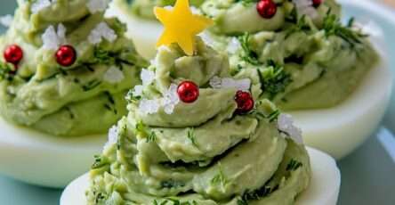 Œufs farcis garnis de guacamole en forme de sapins de Noël, décorés de perles rouges et d’étoiles de fromage.