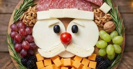 Plateau apéro en forme de visage de Père Noël composé de saucisson, fromages, olives, tomate cerise et fruits.