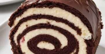 Roulade Forêt-Noire au chocolat garnie de crème fouettée et de cerises, décorée de copeaux de chocolat.