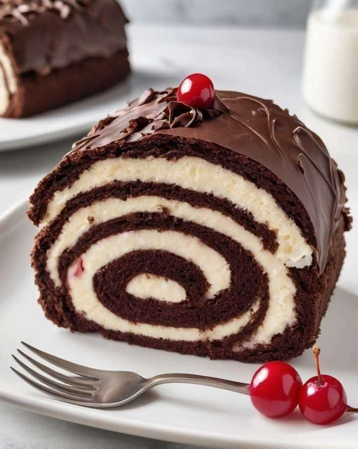Roulade Forêt-Noire au chocolat garnie de crème fouettée et de cerises, décorée de copeaux de chocolat.