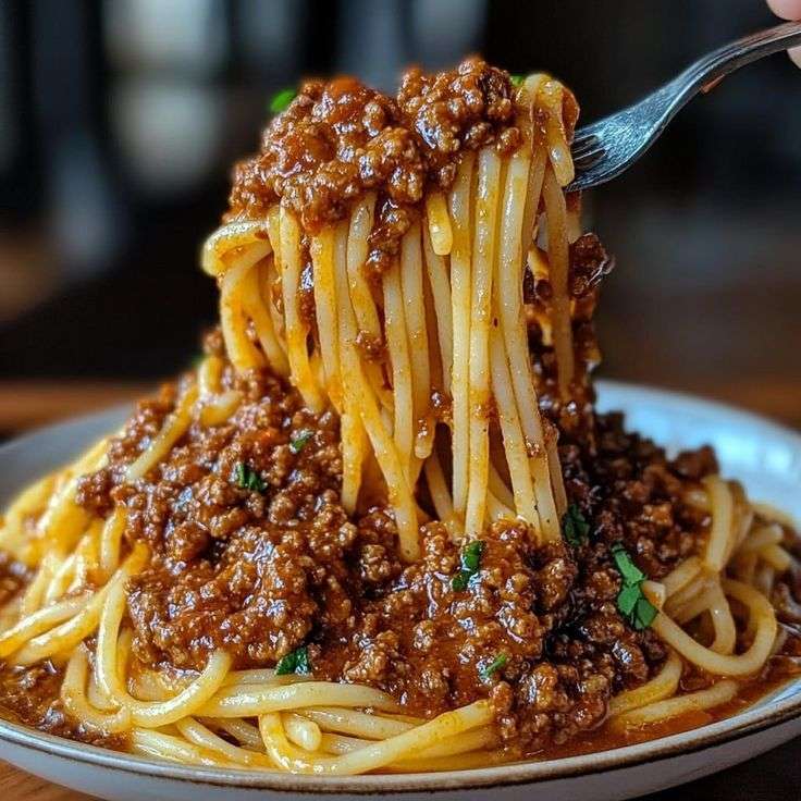 Spaghetti à la bolognaise nappés de sauce tomate au bœuf mijotée, servis avec parmesan râpé.