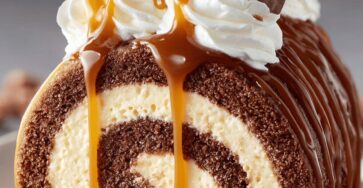 Gâteau moka roulé nappé de caramel, garni de crème vanille et décoré de morceaux de chocolat.