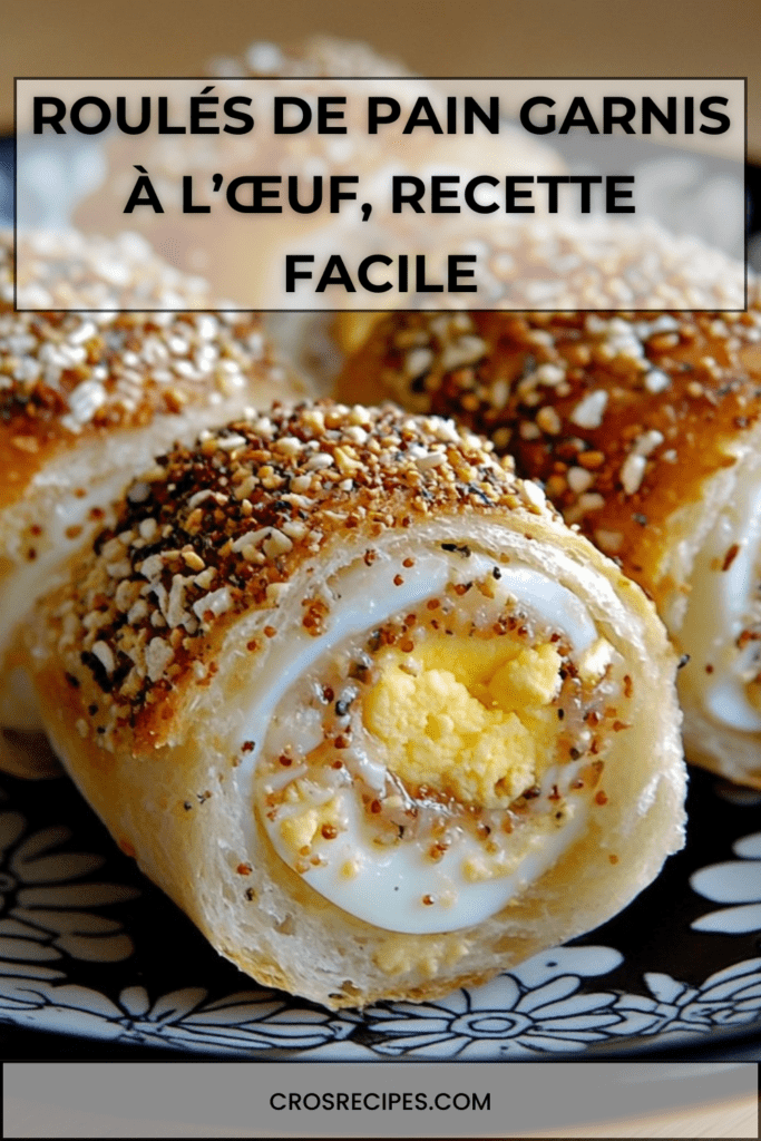 Roulés de pain garnis à l’œuf, dorés au four et roulés dans des graines de sésame, présentés en tranches montrant l’œuf dur au centre