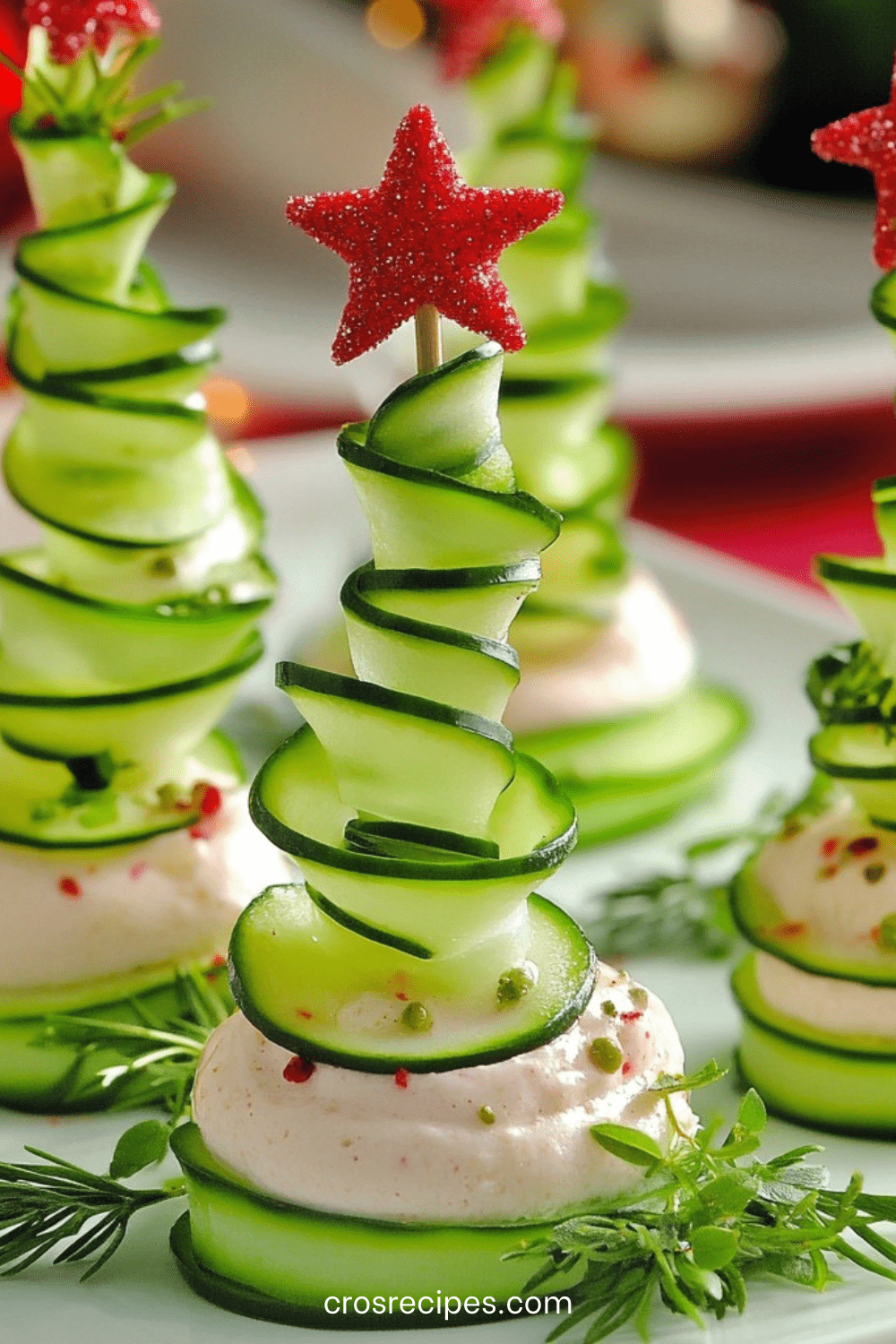 Sapins apéritifs en rubans de concombre posés sur une base de fromage frais aux herbes avec étoile rouge décorative.