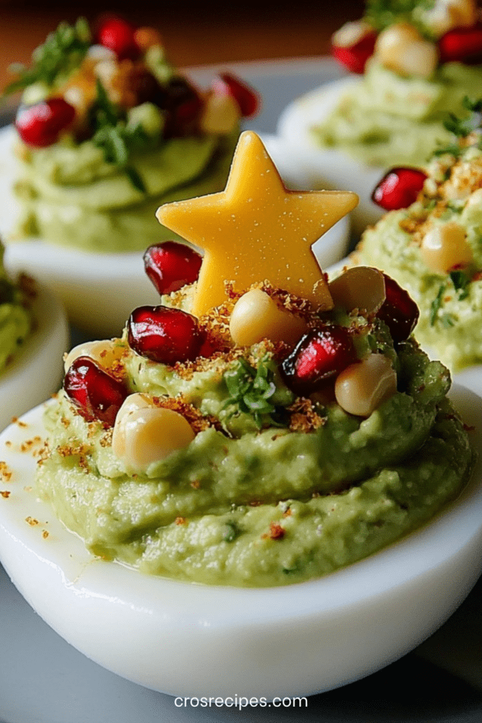 Œufs durs décorés en forme de sapins de Noël, garnis de guacamole vert et de graines de grenade rouges.