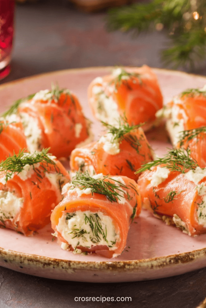 Roulés de saumon fumé garnis de fromage frais et d’aneth, découpés en bouchées et disposés sur un plat de service