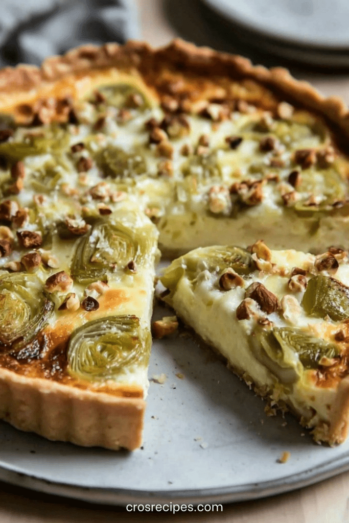 Quiche dorée aux poireaux rôtis, comté fondu et noisettes concassées, servie en parts avec une garniture fondante et un dessus légèrement gratiné