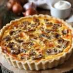 Quiche au poulet dorée, champignons et fromage dans un moule à tarte.