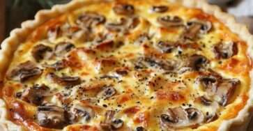Quiche au poulet dorée, champignons et fromage dans un moule à tarte.