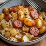 Poêlée de kielbasa dorée avec pommes de terre et chou émincé dans une cocotte en fonte.