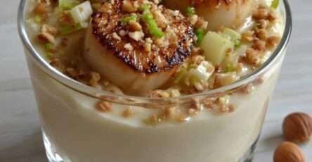 Verrines gastronomiques de Saint-Jacques poêlées posées sur une crème de panais, décorées de noisettes et oignon nouveau.