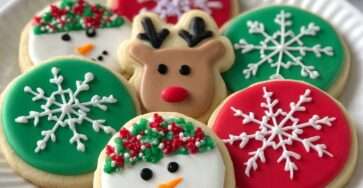 Biscuits de Noël décorés avec glaçage coloré en flocons, rennes et bonhommes de neige, prêts à être dégustés.