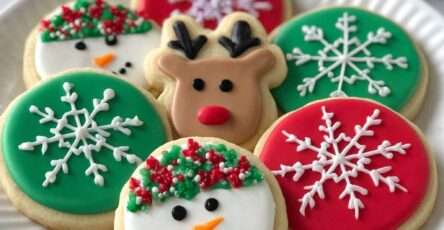 Biscuits de Noël décorés avec glaçage coloré en flocons, rennes et bonhommes de neige, prêts à être dégustés.