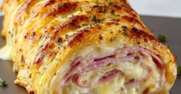 Roulé feuilleté au jambon et fromage doré au four, tranché et servi chaud avec une salade.