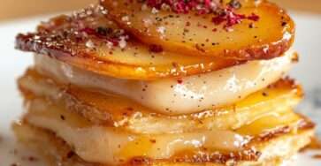 Mille-feuille feuilleté croustillant aux pommes caramélisées et fromage fondant, finition poivre et baies roses.