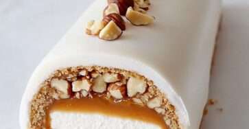 Bûche glacée vanille avec cœur caramel beurre salé et éclats de noisettes, servie en dessert festif.