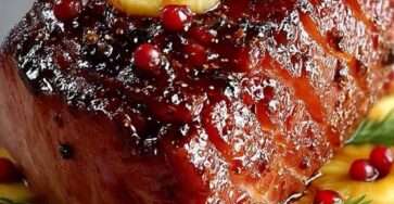 Rôti de jambon glacé à l’ananas et cranberries, servi avec une sauce brillante sucrée-salée.