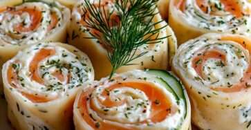 Roulés au saumon fumé et fromage frais aux herbes, coupés en spirales régulières et dressés sur un plateau festif.