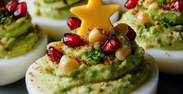 Œufs durs décorés en forme de sapins de Noël, garnis de guacamole vert et de graines de grenade rouges.