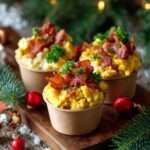 Mini-cups d’œufs brouillés crémeux garnis de bacon croustillant et d’herbes fraîches, servis en portions individuelles.