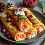 Crêpes roulées garnies de fromage frais citronné, saumon fumé, aneth et canneberges, dressées en entrée festive.