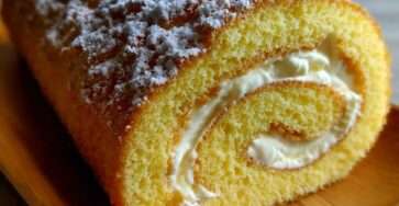 Bûche roulée à la génoise vanille Bourbon garnie de crème mascarpone citron, décorée de sucre glace, découpée en tranches montrant une spirale régulière