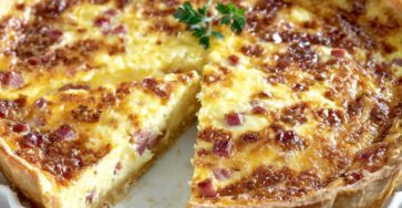 Part de quiche jambon fromage dorée et gratinée, servie dans un moule à tarte avec une garniture crémeuse au jambon et fromage
