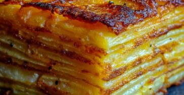 Plat de Pommes Anna croustillantes découpées en parts nettes, montrant de fines couches régulières de pommes de terre dorées et beurrées