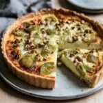 Quiche dorée aux poireaux rôtis, comté fondu et noisettes concassées, servie en parts avec une garniture fondante et un dessus légèrement gratiné