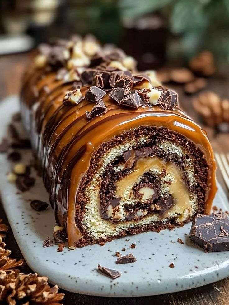 Gâteau roulé au chocolat garni de caramel et noix de pécan avec glaçage chocolat brillant sur le dessus.