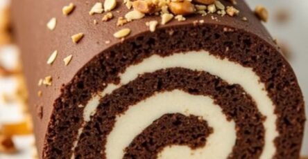 Gâteau roulé au chocolat garni de crème onctueuse, nappé de sauce caramel et décoré de cacahuètes concassées.
