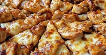 Pizza au poulet barbecue dorée au four avec mozzarella fondante, oignons rouges émincés et coriandre fraîche, servie chaude sur une planche en bois.