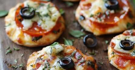 Mini-pizzas apéritives garnies de sauce tomate, mozzarella fondue et tranches de pepperoni, dorées au four et servies sur une plaque