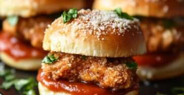 Mini-sandwichs garnis de poulet croustillant pané au parmesan, salade verte et sauce, servis dans de petits pains moelleux